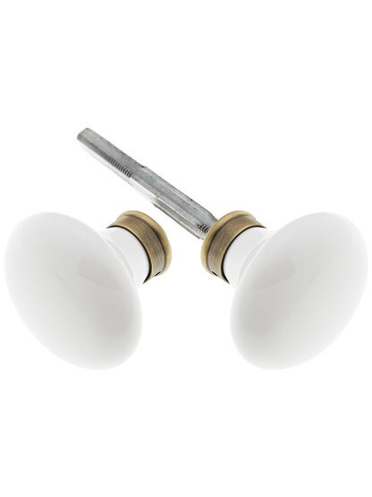 Pair of White Porcelain Door Knobs With Solid Brass Shank in Antique Brass.